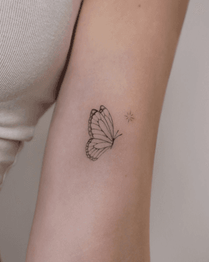 Fine-line and illustrative tattoo of a minimal butterfly with a touch of sparkle, done by Constanza.