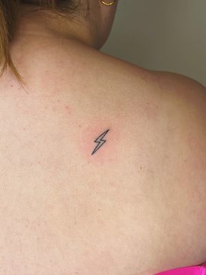 A fine-line lightning bolt tattoo done by Laura, using the hand-poke technique for a unique, detailed design.