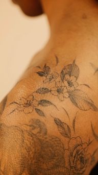 Delicate cherry blossoms and peony flowers in black and grey, made with the freehand method, flowing seamlessly on the arm, shoulder and collar bone, made on the darker skin tone, floral gap filler