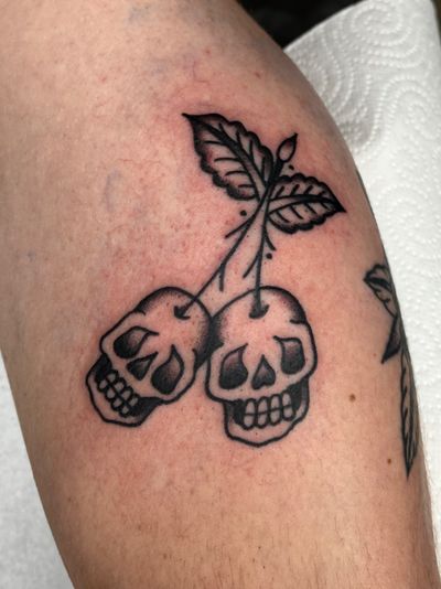 Black and gray traditional style tattoo featuring a detailed skull and cherry motif, created by Clara Colibri.