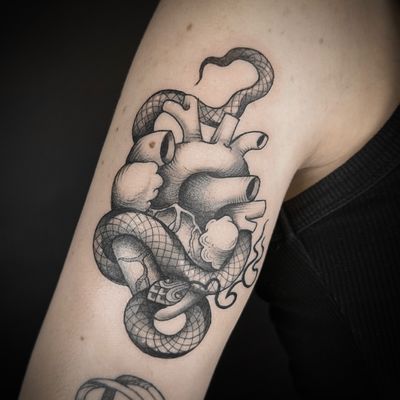 A stunning black and gray tattoo featuring a snake entwined around a heart, with beautiful dotwork and illustrative style by the talented artist Jenny Dubet.