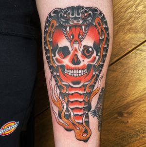 Get inked with this captivating traditional tattoo featuring a snake and skull design, expertly done by tattoo artist Megan Foster.