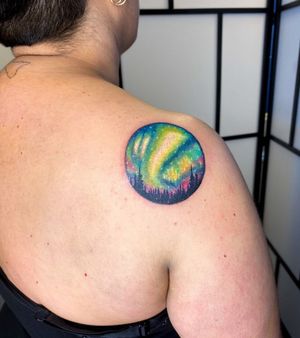 Experience the magic of the northern lights dancing above a serene forest in this stunning watercolor tattoo by Alfonso Barberio.