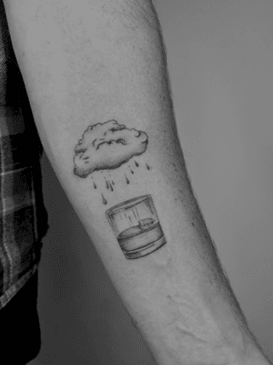 Delicate micro-realism tattoo by Ruth Hall captures a glass with a cloud inside, raindrops gently falling around it.