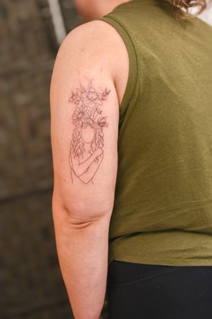 Beautiful illustrative tattoo by Steffan Eagle featuring an outline of a woman surrounded by delicate nature and flower motifs.