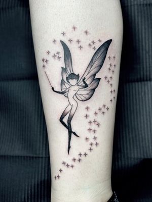 Get lost in the whimsical world of this black and gray illustrative tattoo by Amandine Canata. Featuring a mystical fairy surrounded by twinkling stars.