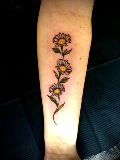 An illustrative tattoo by Ben Twentyman featuring a vibrant daisy vine design in full color.