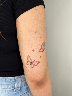 Delicate fine line tattoo featuring a star, butterfly, and sparkle design by Emma InkBaby.