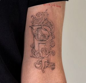 Elegant black_and_gray fine_line tattoo featuring a cherub and filigree letter by talented artist Jo Heatley.