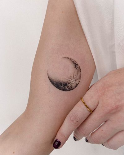 Get mesmerized by the detailed black and gray moon tattoo expertly crafted by artist Alex Caldeira. Embrace the beauty of the night sky with this stunning piece of art.