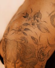 Delicate cherry blossoms and peony flowers in black and grey, made with the freehand method, flowing seamlessly on the arm, shoulder and collar bone, made on the darker skin tone, floral gap filler