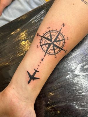 Blackwork compass with ornamental airplane, symbolizing travel and adventure, by Epic Tattoos Guildford.