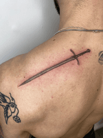 Get a stunning black and gray illustrative sword tattoo by the talented artist Charlie Macarthur.