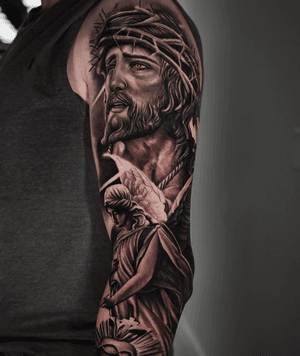 A realistic black and gray tattoo featuring Jesus and an angel, creating a powerful religious motif, by Ember.