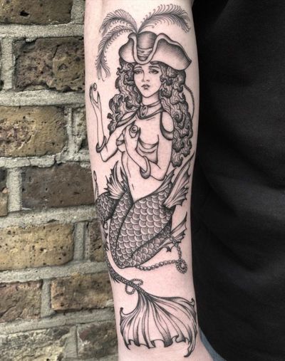 Stunning black and gray neo-traditional tattoo by Amandine Canata, featuring a pirate and mermaid hat motif. A unique and detailed design.