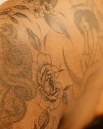 Delicate cherry blossoms and peony flowers in black and grey, made with the freehand method, flowing seamlessly on the arm, shoulder and collar bone, made on the darker skin tone, floral gap filler