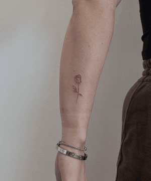 Fine line tattoo by Oliver Soames featuring a delicate outlined rose design.