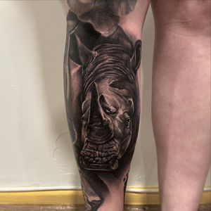 Capture the strength and beauty of the majestic rhinoceros with this stunning black and gray tattoo by the talented artist Lawrence Canham.