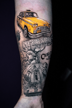 A black and gray realistic tattoo featuring a yellow cab, the Statue of Liberty, and the United States for a truly patriotic tribute by Warren Mullins.