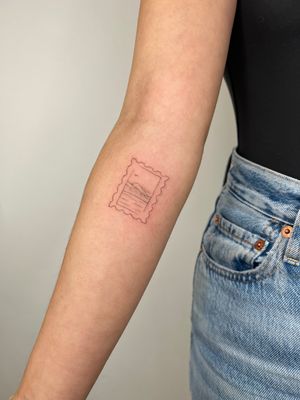 A detailed fine line, illustrative tattoo of a picturesque landscape resembling a vintage postal stamp, created by tattoo artist Emma InkBaby.