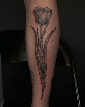 Experience the elegance of a black and gray tulip tattoo, expertly crafted by Kat Jennings in an illustrative style.
