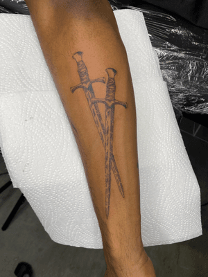 Illustrative tattoo of a sword with intricate engraving details, in a sketch style by artist Charlie Macarthur.