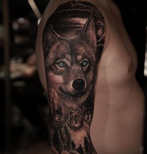 A black and grey realistic tattoo featuring a pack of wolves in a forest setting, with piercing blue eyes. Created by Ember.