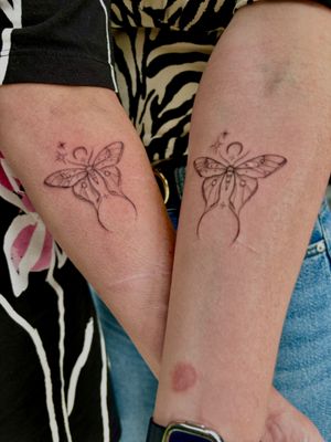 A mesmerizing black and gray tattoo featuring a moon, stars, and moths in fine line and dotwork style by Ruth Hall, creating a matching sparkle effect.