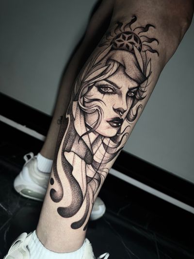 A stunning black and gray tattoo featuring a powerful woman with intricate patterns and a radiant sun motif, created by the talented artist Hamid.