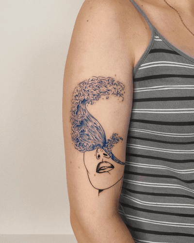 A fine line illustration of a woman's face blending into a flowing blue wave, created by artist Alona Hamova.