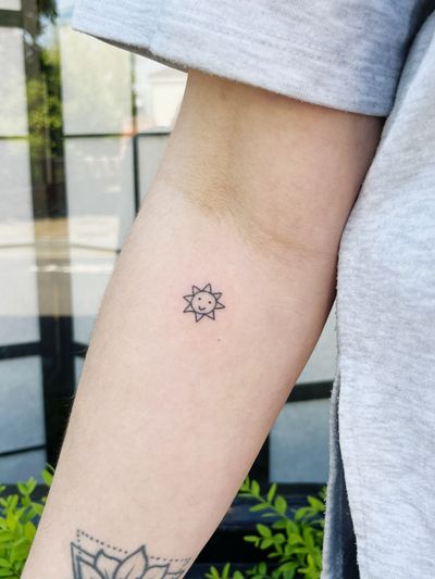 Fine line hand-poked sun tattoo, artistically crafted by Laura in an ignorant style.