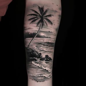Capture the serene beauty of the ocean and beach with this black and gray tattoo by Craig Hicks. Perfect for nature lovers.