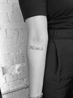 A minimalist tattoo featuring a thin black line outlining a London city skyline on the inner forearm.
