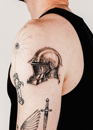 Capture the intricate detail of a knight's helm and armor in this black and gray micro realism tattoo by Gabriele Edu.