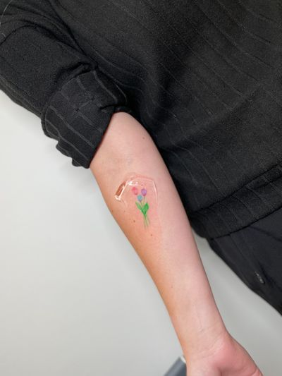 Illustrative style tattoo by Vera featuring a colorful and delicate flower motif.