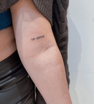 Get a timeless and delicate date tattoo with fine line and small lettering by renowned artist Alfonso Barberio. Perfect for commemorating special memories or events.