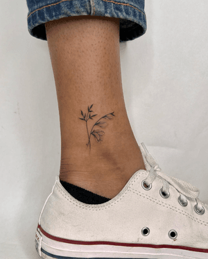 Fine line floral tattoo featuring a delicate botanical flower motif by Marissa Boulay.