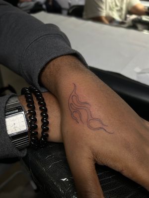 Fine line, illustrative, traditional tattoo by Ellie Shearer featuring a dark skin motif engulfed in flames.