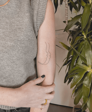 Fine line tattoo of a single line art Gemini baby face, done by Alexey.