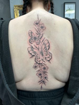 Experience the delicate beauty of Ellie Shearer's black & gray dotwork butterfly, flower, and vine tattoo design.