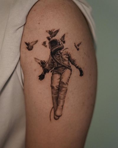 Detailed black and gray micro realism tattoo of an astronaut accompanied by a bird and dove, created by Kenny Go.