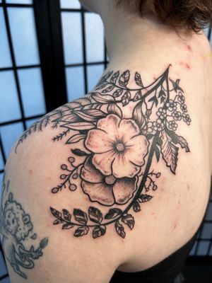 A stunning blackwork tattoo featuring intricate tree, flower, branch, and plant motifs by the talented artist Jonathan Glick.
