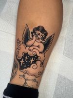 Black and grey coverup tattoo of a cherub resting on a cloud. 