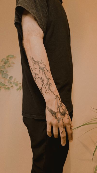 Black and gray tattoo by Milky Blue featuring a swallow perched on a tree branch created with intricate dotwork.