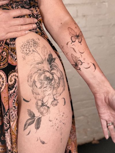 Alex Caldeira's fine line black and gray tattoo features a delicately intricate blend of chrysanthemum flower and butterfly motifs.