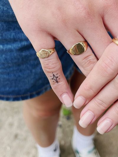 A fine line, hand-poked ornamental star tattoo created by artist Laura.