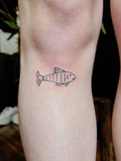 Laura's delicate fine line hand-poked fish design exudes elegance and fluidity.