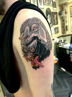 Illustrative and traditional tattoo of a wolf and sheep facing off, beautifully executed by Barney Coles.
