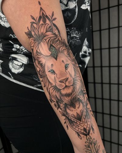 A stunning black and gray dotwork tattoo of a lioness surrounded by intricate floral and jewel motifs, by Alice Hope Tattoo.