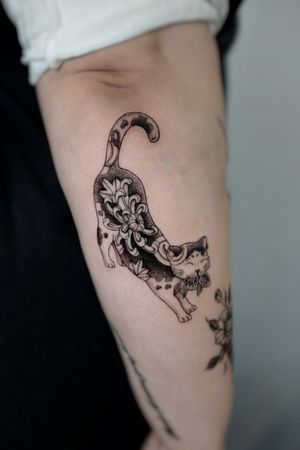 An intriguing black and gray dotwork tattoo by Andrea featuring a cat and koi fish in a traditional Japanese pattern style.